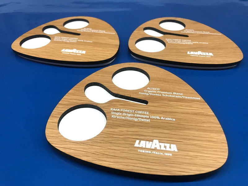 Hochwertige Holzplatten mit präziser Laserbearbeitung und UV-Druck für Lavazza-Kaffeetastings, mit ausgestanzten Vertiefungen für Proben und edler Holzoptik.